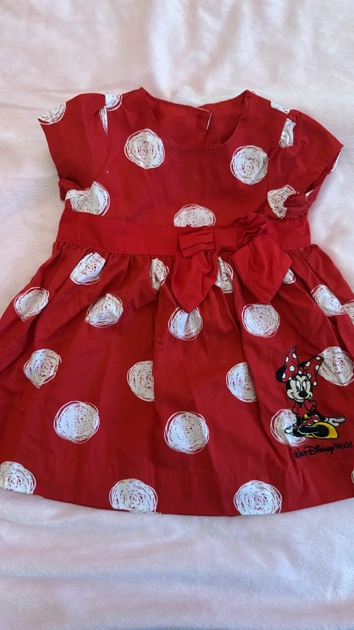 Vestido rojo de niña con lunares blancos y estampado de Minnie Mouse. Ideal para un look casual y divertido.