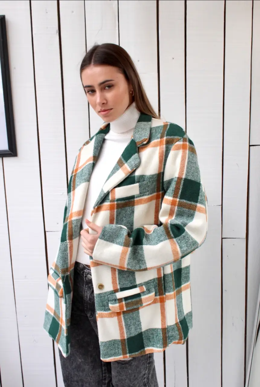 Blazer a cuadros en tonos verde, blanco y naranja. Ideal para un look casual y moderno. Perfecto para combinar con jeans o pantalones de vestir.