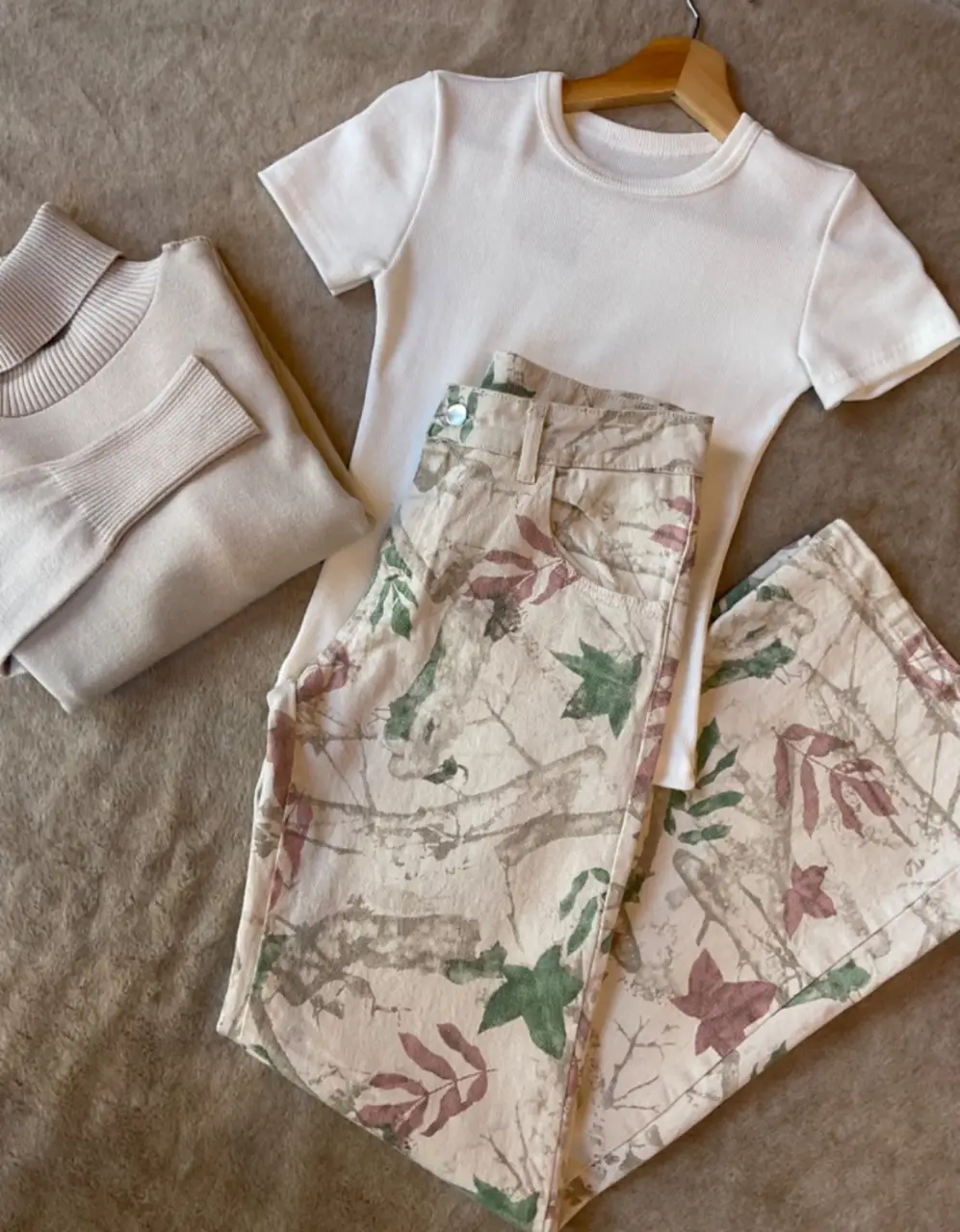 Pantalón suelto con estampado de hojas en tonos verdes y borgoña sobre fondo crudo. Ideal para un look casual y cómodo.