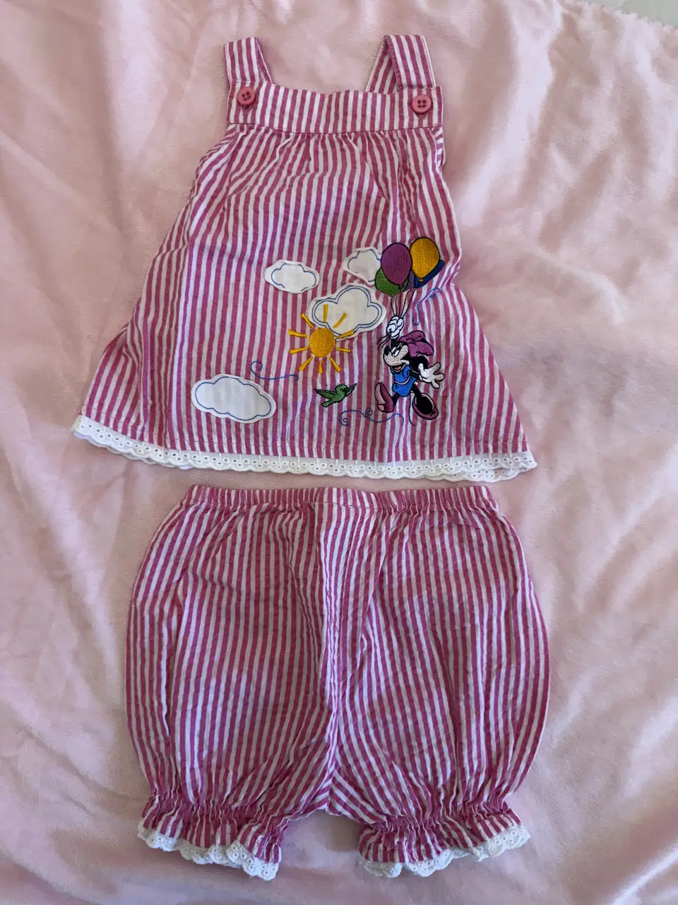 Conjunto de niña a rayas rosas y blancas, con estampado de Minnie Mouse. Incluye un vestido con tirantes y volados de encaje, y un short a juego.
