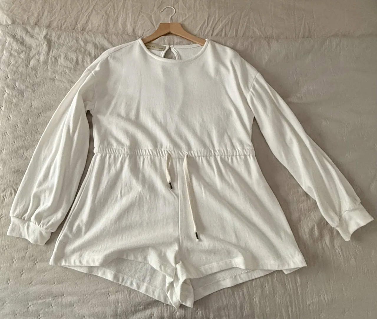 Mono blanco de manga larga con cordón ajustable en la cintura. Ideal para un look casual y cómodo.