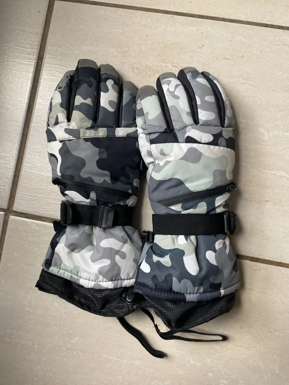 2 guantes de abrigo con diseño camuflado en tonos grises y negros. Ideales para el frío, cuentan con forro interno de plush para mayor calidez y ajuste con hebilla en la muñeca. El precio es por los 2. unisex 
