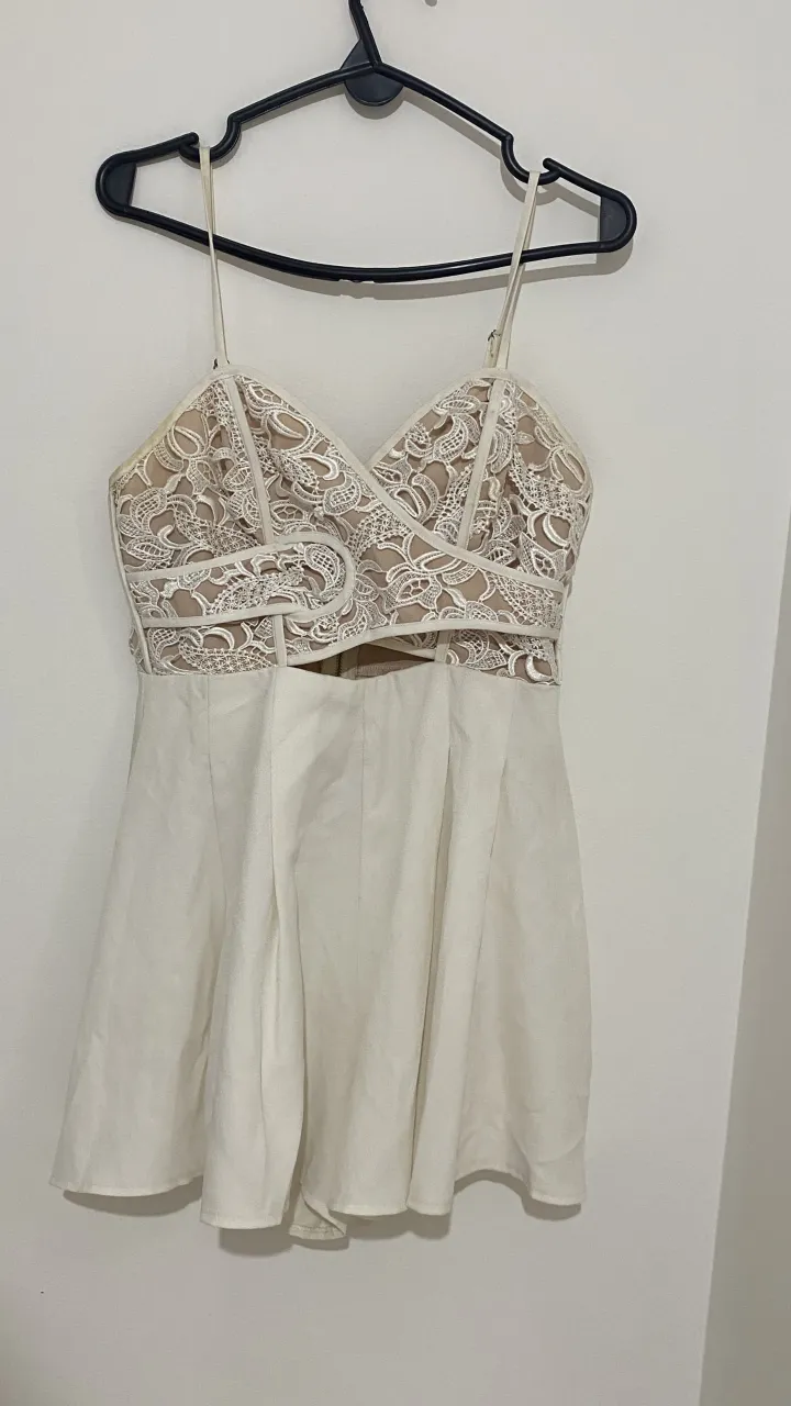 Vestido blanco corto con detalles de encaje en la parte superior y falda plisada. Ideal para eventos especiales o salidas.