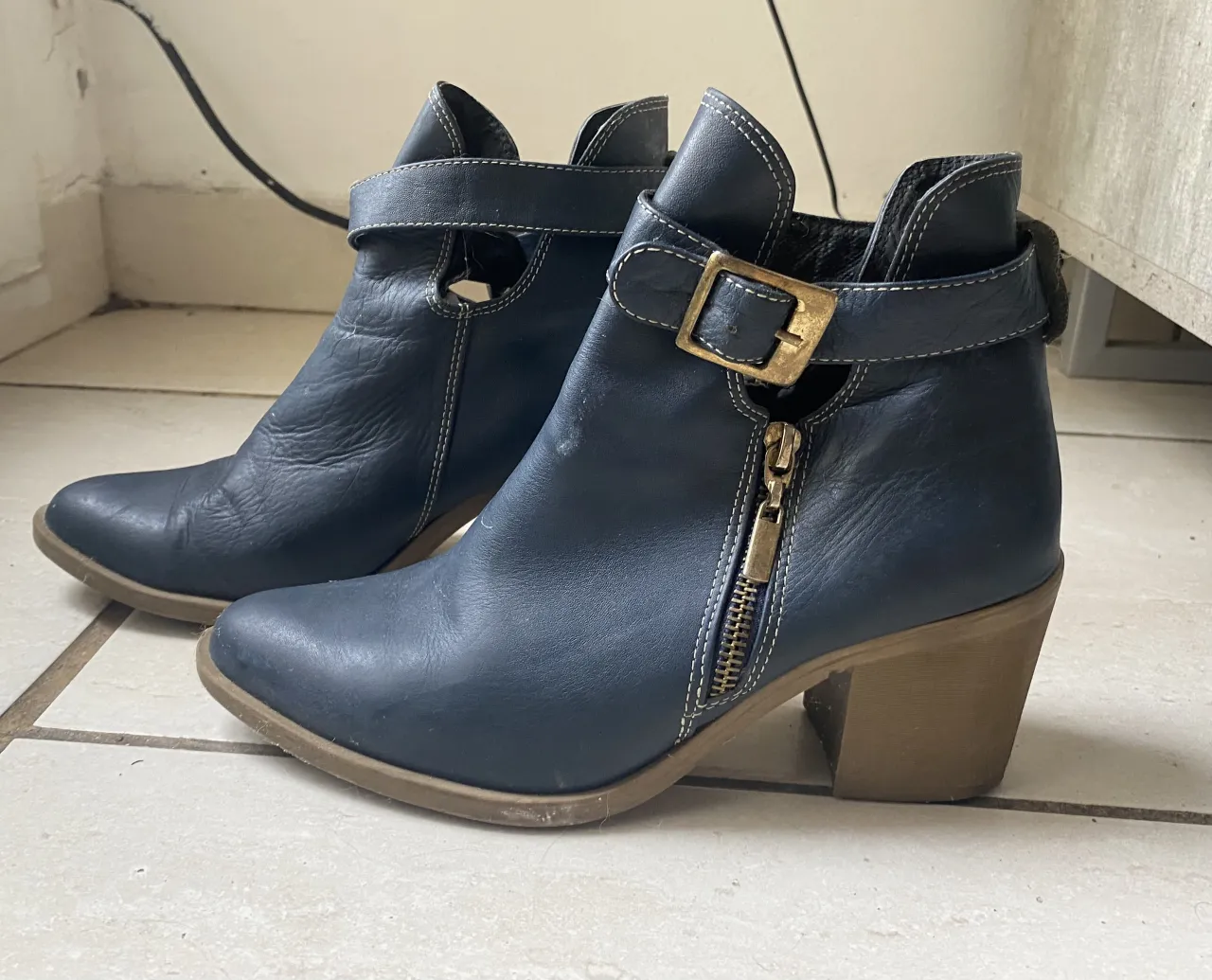 Botitas de cuero azul marino con hebilla y cierre lateral. Taco grueso y punta fina. Ideales para un look canchero y moderno.