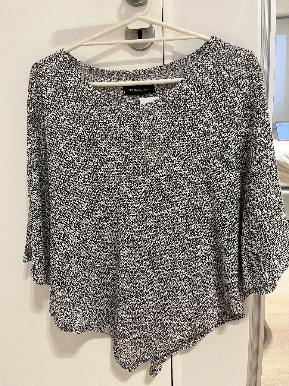 Blusa de mujer (estilo poncho) tejida en blanco y negro. Diseño asimétrico y mangas 3/4. Ideal para un look casual y moderno.