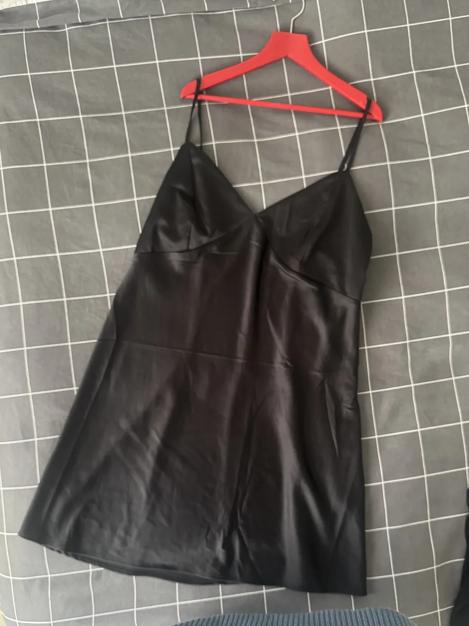 Vestido corto negro de satén con tirantes finos regulables y escote en V. Ideal para una salida nocturna o evento especial. Marca H&M. Talle L