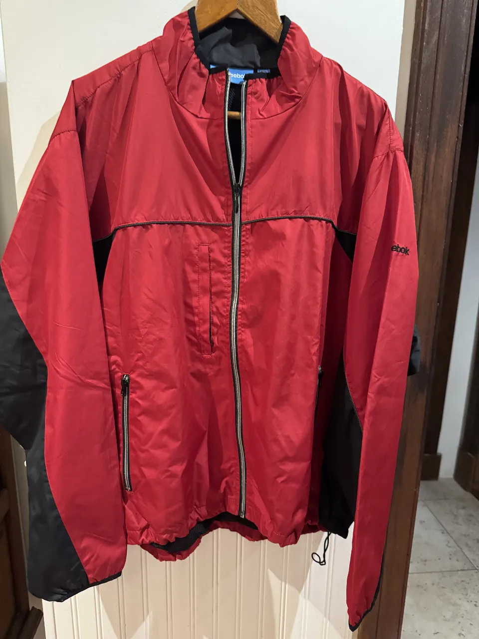 Campera deportiva Reebok roja con detalles en negro. Ideal para actividades al aire libre o para un look casual y cómodo. Con cierre frontal y bolsillos.ORIGINAL