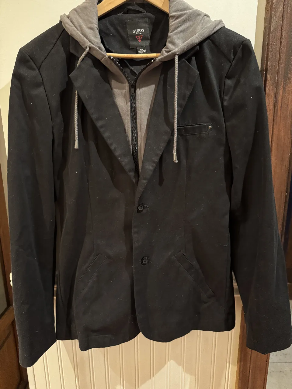 Blazer negro con capucha gris de la marca Guess. Ideal para un look casual y moderno.con buzo desmontable con cierre