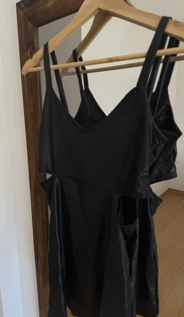 Vestido negro con tiras finas y recortes en la cintura.