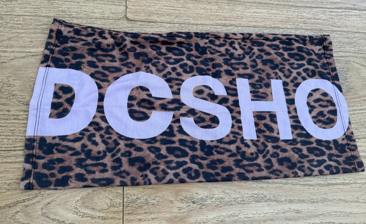 Cuello abrigo  con estampa de leopardo y logo "DCSHO" en color lila.