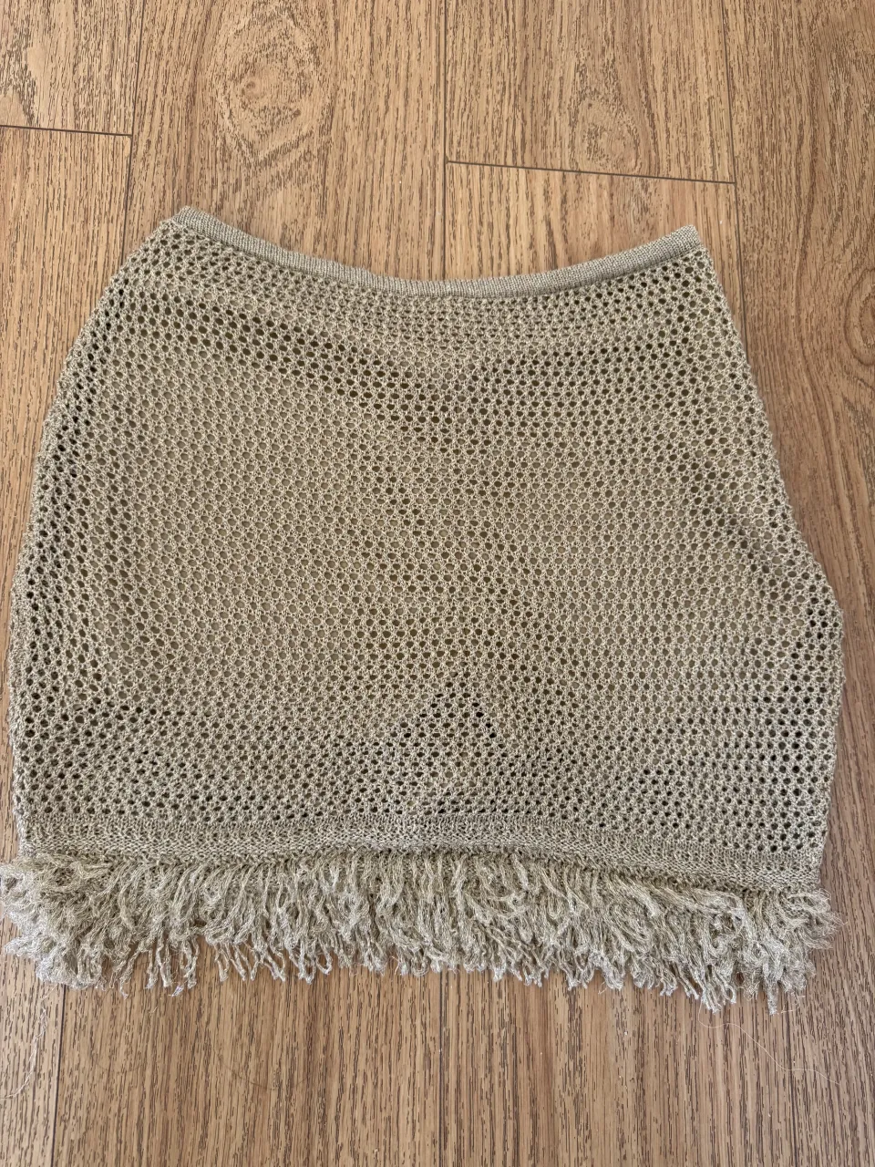 Pollera corta de tejido abierto con flecos en el borde inferior.