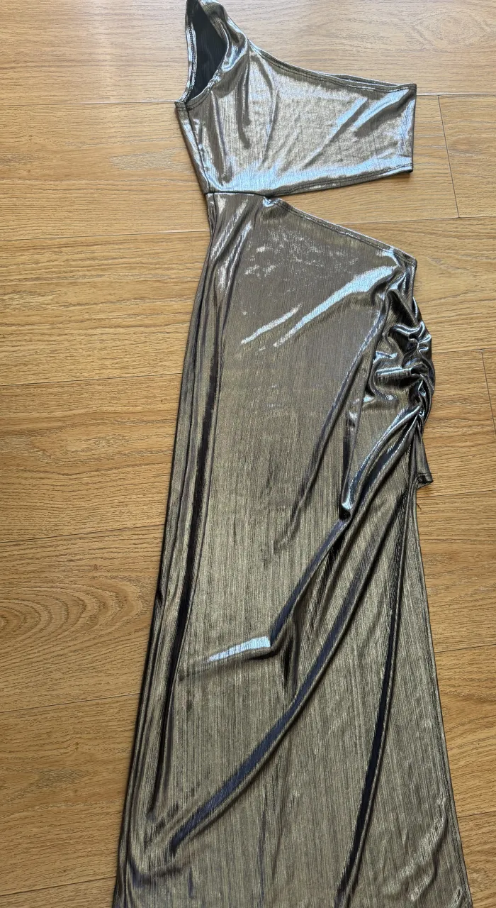 Vestido largo plateado con un solo hombro y detalle fruncido en la cadera.