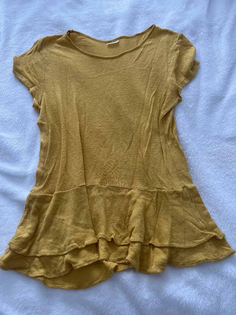 Blusa amarilla con volados en la parte inferior, ideal para un look casual y fresco. Confeccionada en un tejido ligero y cómodo, perfecta para el día a día. de desiderata