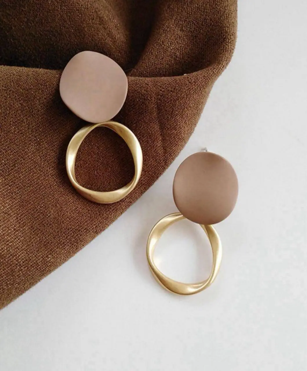Aros colgantes con diseño geométrico. Círculo dorado y detalle superior en color marrón. Ideales para un look moderno y sofisticado.