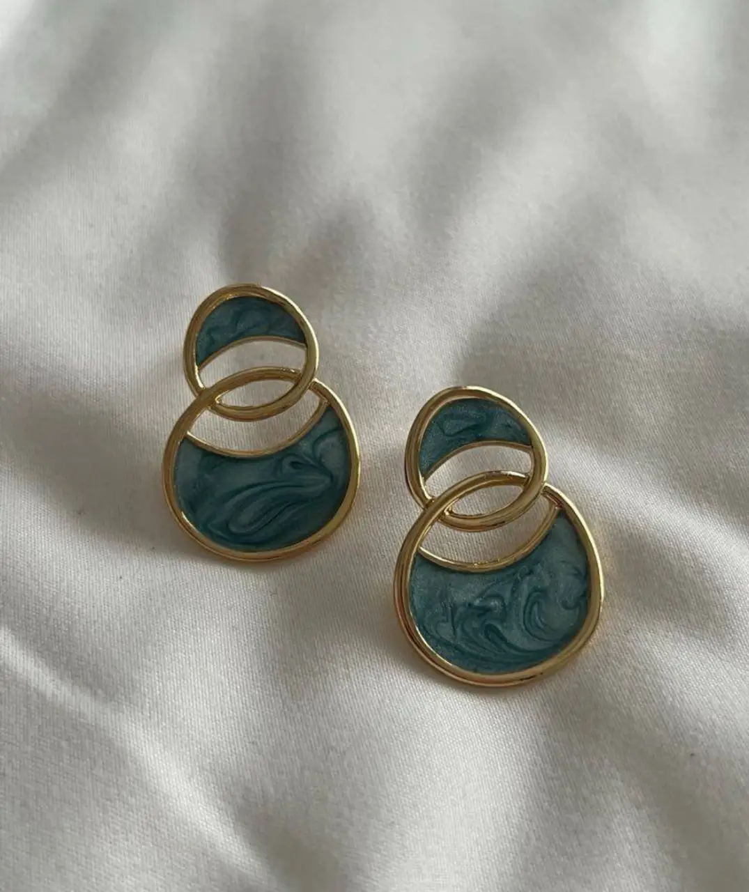 Aros colgantes con diseño de círculos entrelazados, con detalles en dorado y un atractivo color verde. Perfectos para añadir un toque de elegancia y estilo a cualquier look.
