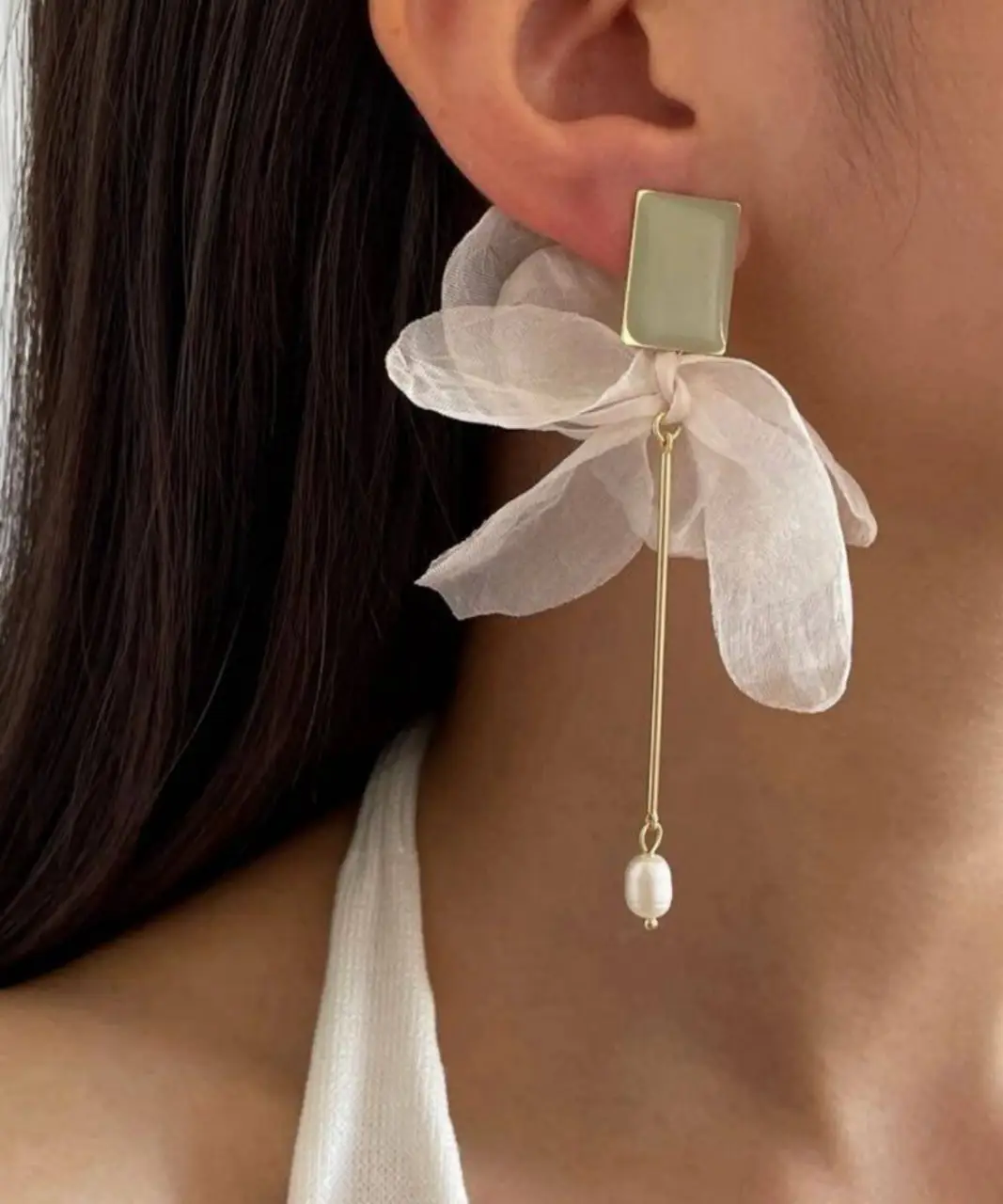 Aros largos con diseño floral de tela y detalle de perla. Ideales para darle un toque romántico y elegante a cualquier look.