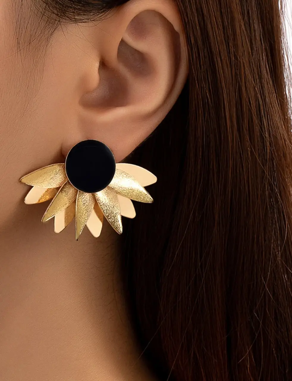 Aros de diseño floral con un círculo negro en el centro y pétalos dorados. Ideales para darle un toque elegante y moderno a cualquier look.