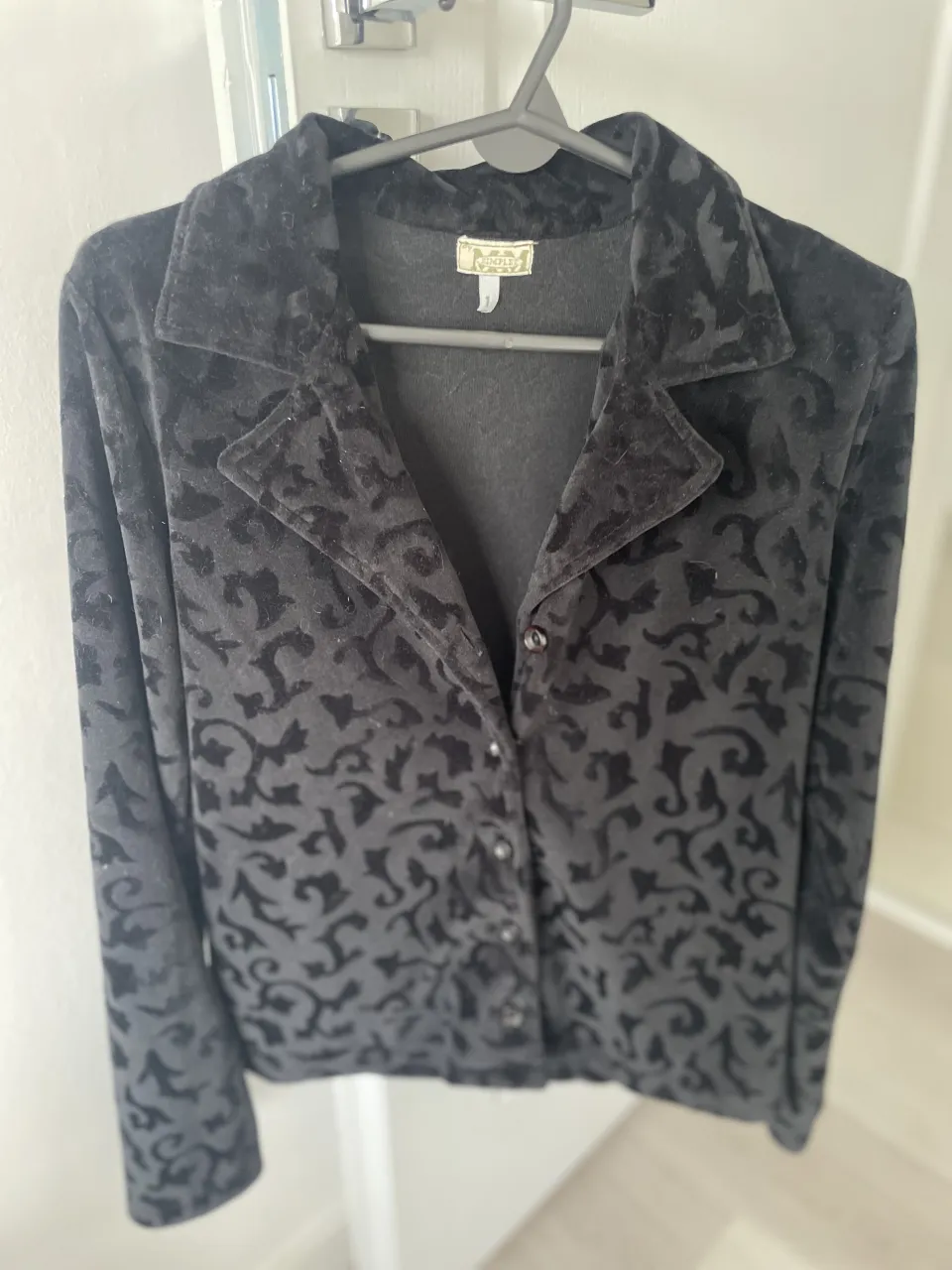 Camisa negra con estampado floral en relieve y botones al frente.