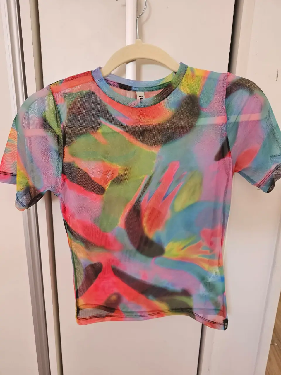 Remera de red con estampado abstracto en tonos vibrantes. Ideal para un look audaz y moderno. Hombro 31cm Sisa 36cm largo 48cm