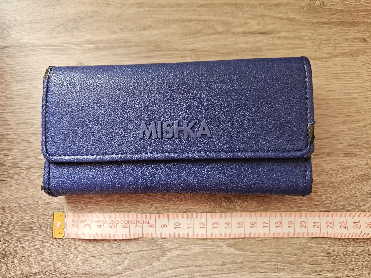 Billetera azul de cuero con cierre y detalle de la marca Mishka en relieve. Cuenta con varios compartimentos internos y un diseño elegante y funcional. Ver las últimas dos fotos que muestran el desgaste.