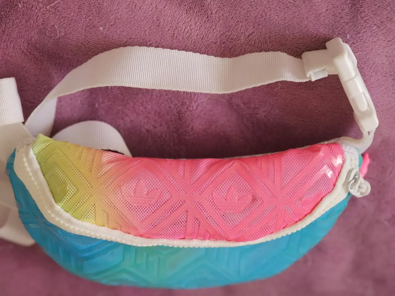 Riñonera deportiva con diseño degradado en tonos azul, rosa y amarillo. Cuenta con correa ajustable y cierre. Ideal para llevar tus esenciales con estilo y comodidad.