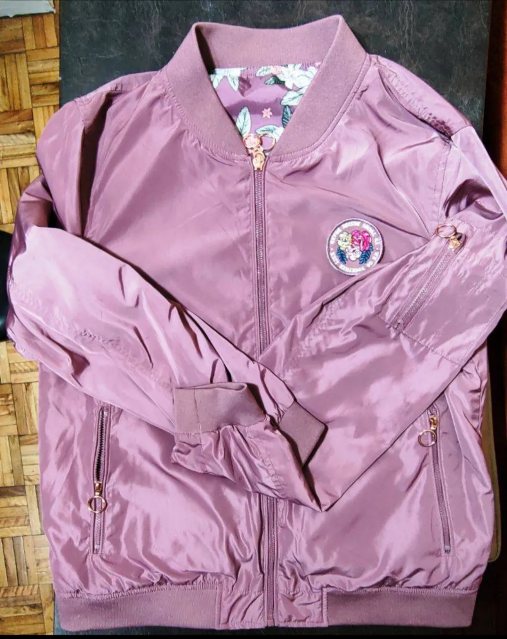 Campera rompeviento reversible bomber 
color tipo rosa viejo del lado liso, y del otro lado floreado combinado con el color de fondo.Los cierres son una bomba, tipo color dorado/ocre que le da un contraste increíble! 
Tanto del lado liso como del floreado tiene sus dos bolsillos laterales y uno en el brazo. 

Las medidas totales son: 
largo de hombros a la cintura 62 cm
de sisa  55 cm 
largo de manga 65 cm