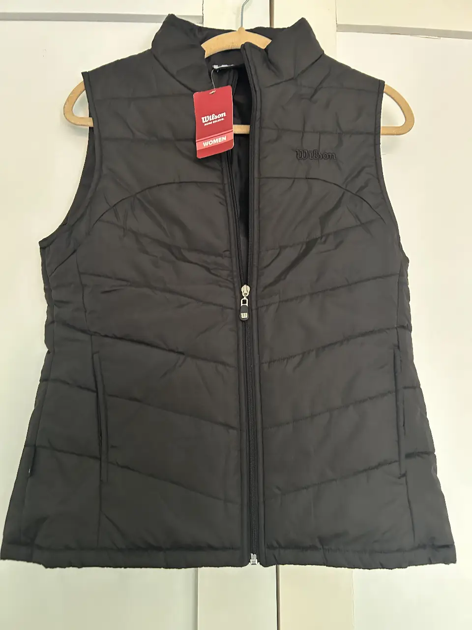 Chaleco acolchado negro de la marca Wilson para mujer. Ideal para usar en días frescos, con cierre y bolsillos.