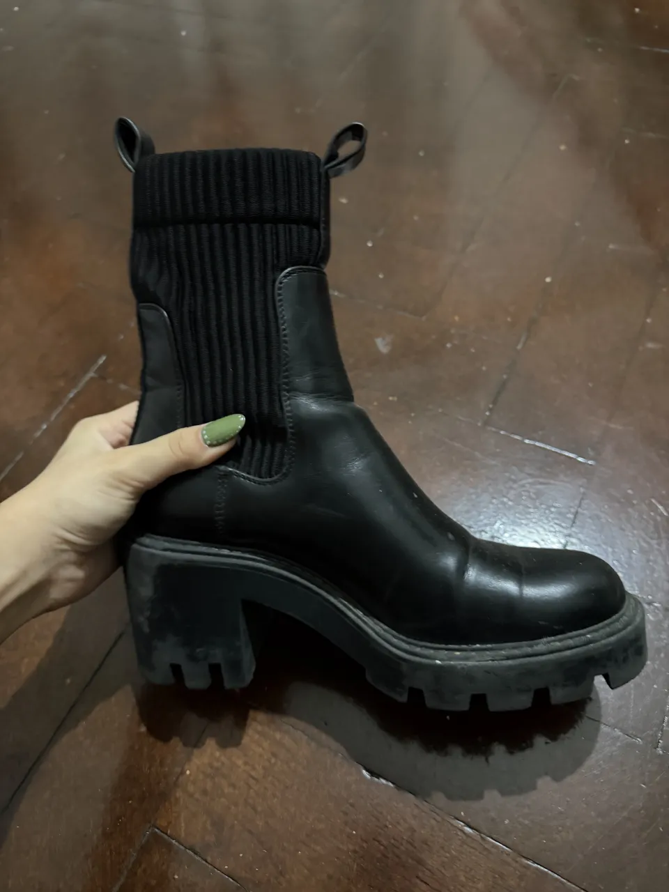 Botas negras con plataforma y taco grueso. Caña de cuero con elástico a los costados y detalle de tejido acanalado en la parte superior de la caña. Dos tiras de tela en la parte trasera para facilitar el calce.