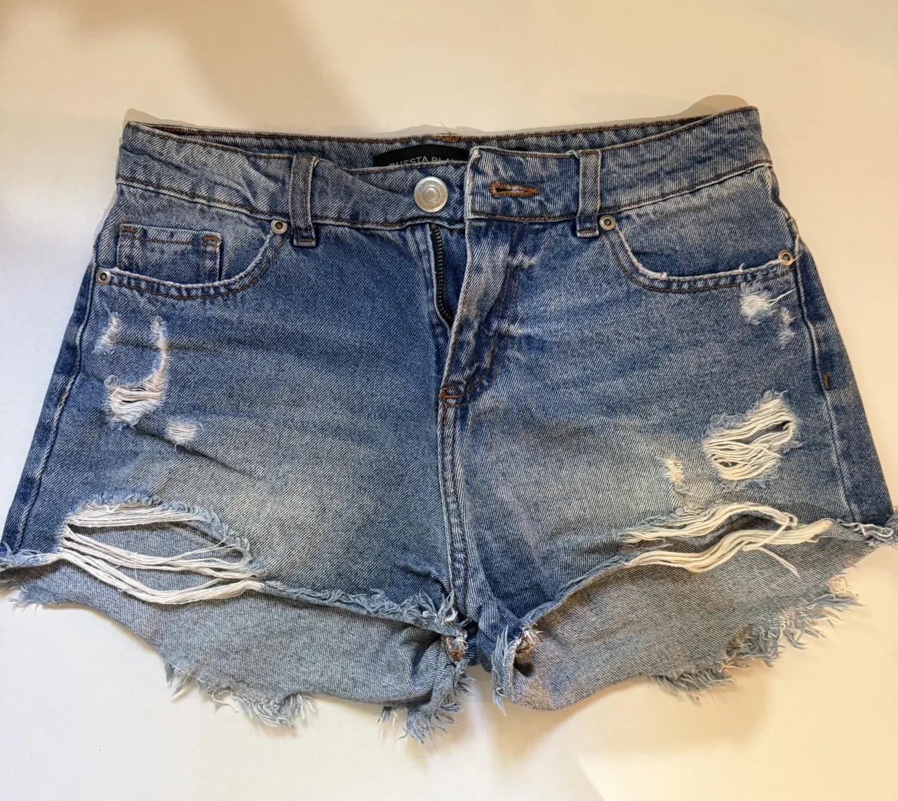 Shorts de jean tiro medio, con roturas y detalles desflecados en los bordes. Un clásico para el verano, súper cómodos y cancheros. Talle 40!