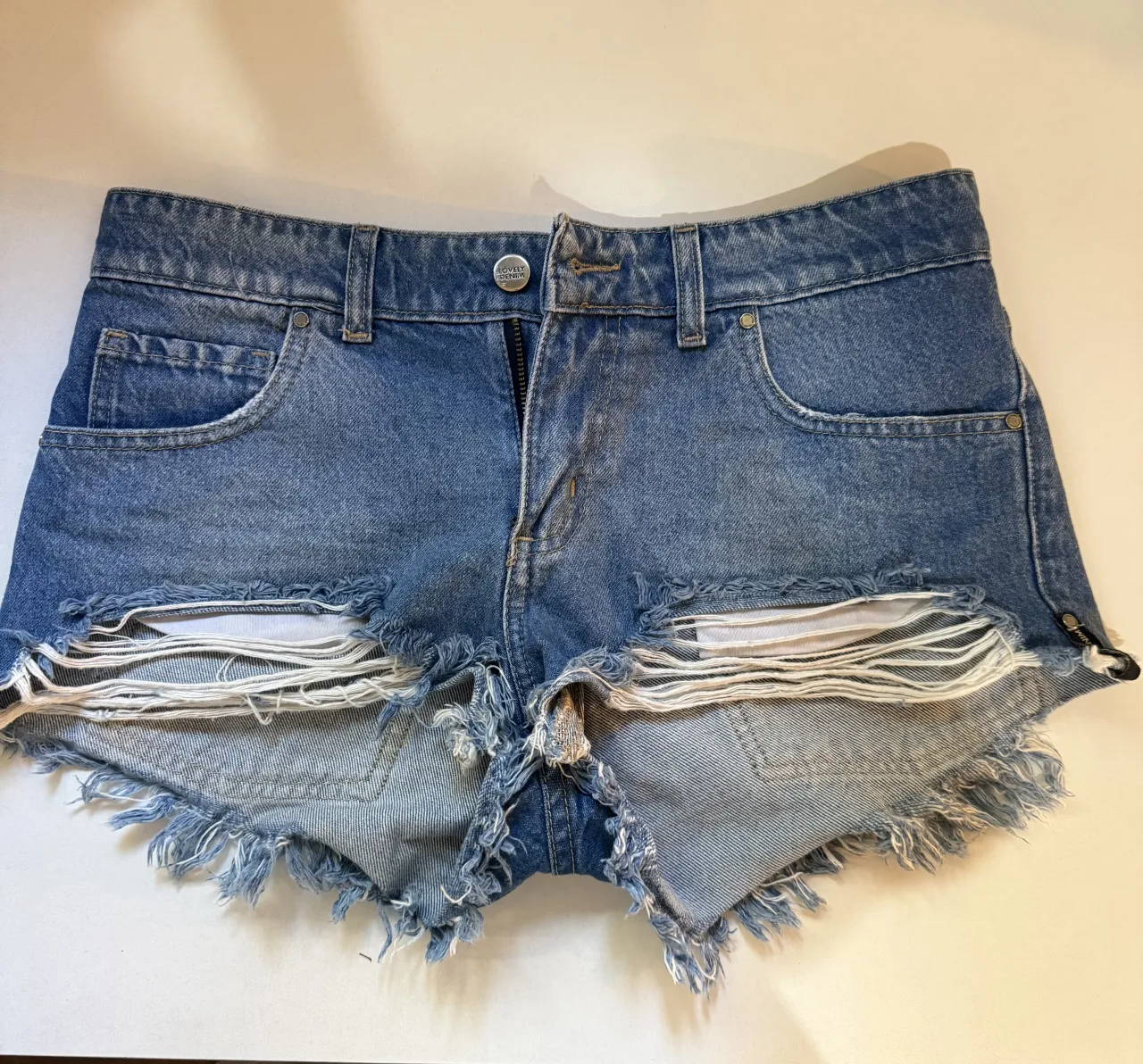 Shorts de jean tiro bajo con roturas y detalles desflecados. Un clásico para un look canchero y moderno.