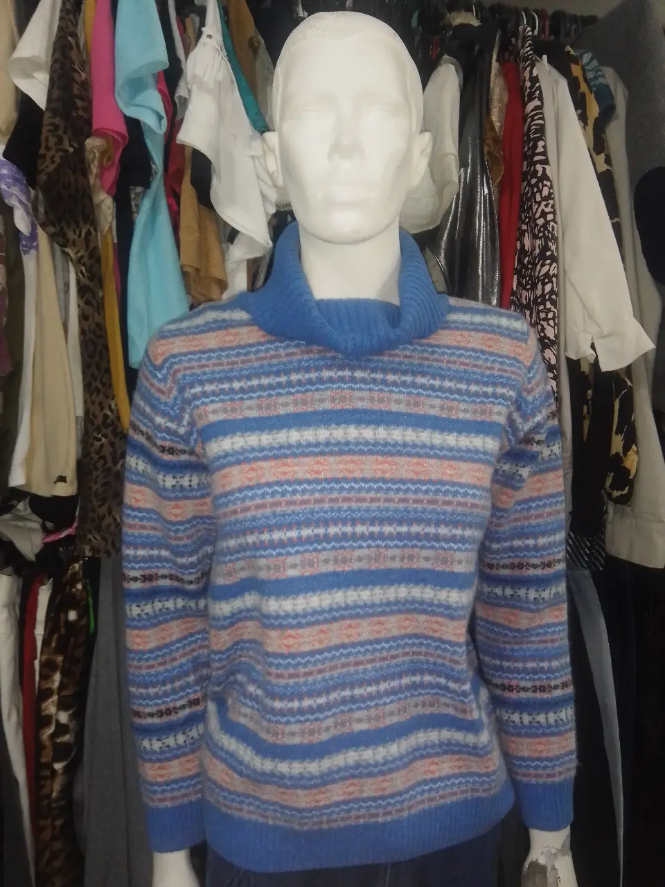 Sweater de cuello alto con diseño a rayas en tonos azules, blancos y detalles en rojo. Ideal para un look casual y abrigado.