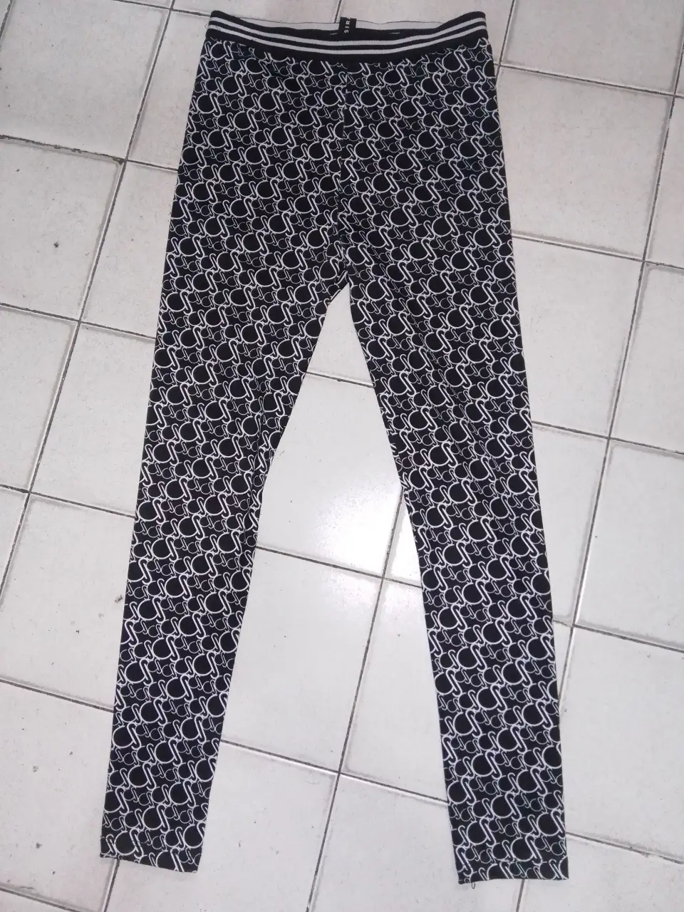 Calzas deportivas para mujer con estampado repetitivo en blanco y negro. Ideales para entrenar o para un look casual.