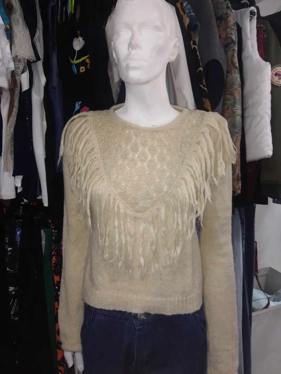 Sweater largo de color crudo con flecos en el pecho. Ideal para un look bohemio y casual.
