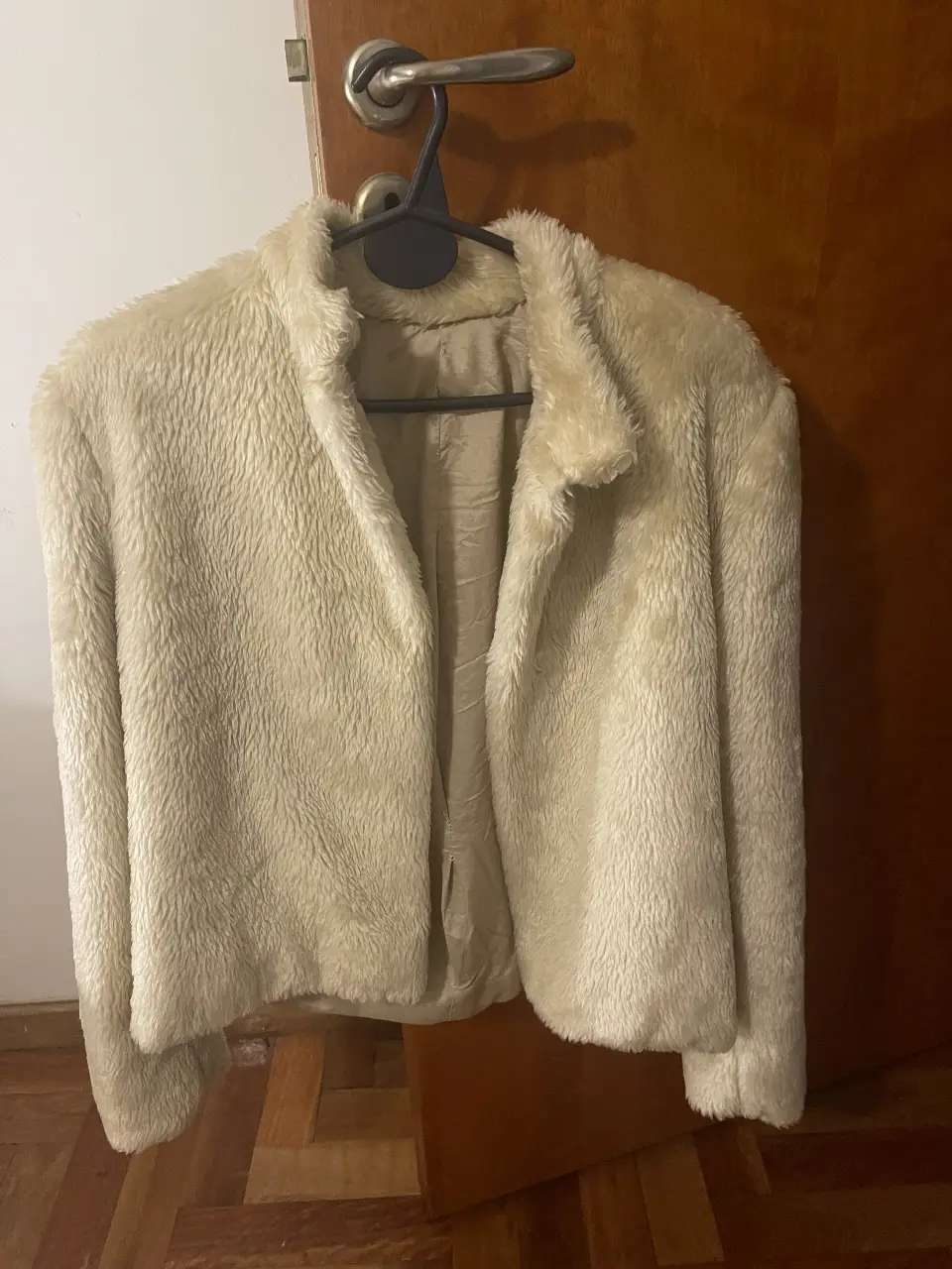 Campera de abrigo estilo bomber, confeccionada en un tejido suave y peludo de color crudo. Ideal para un look casual y abrigado.