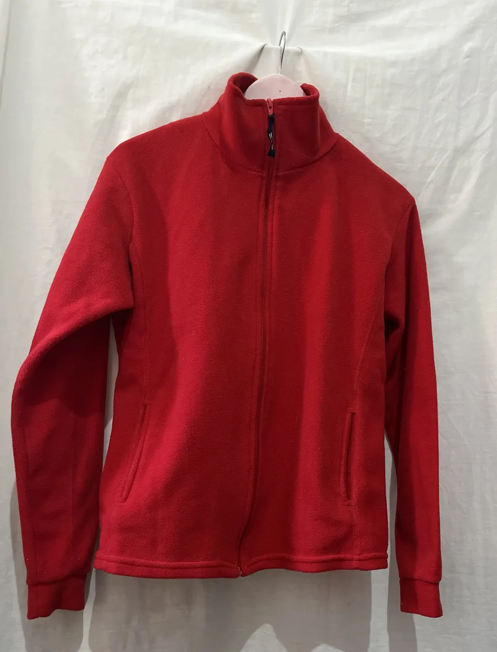 Campera deportiva roja con cuello alto y cierre completo. Posee bolsillos laterales.