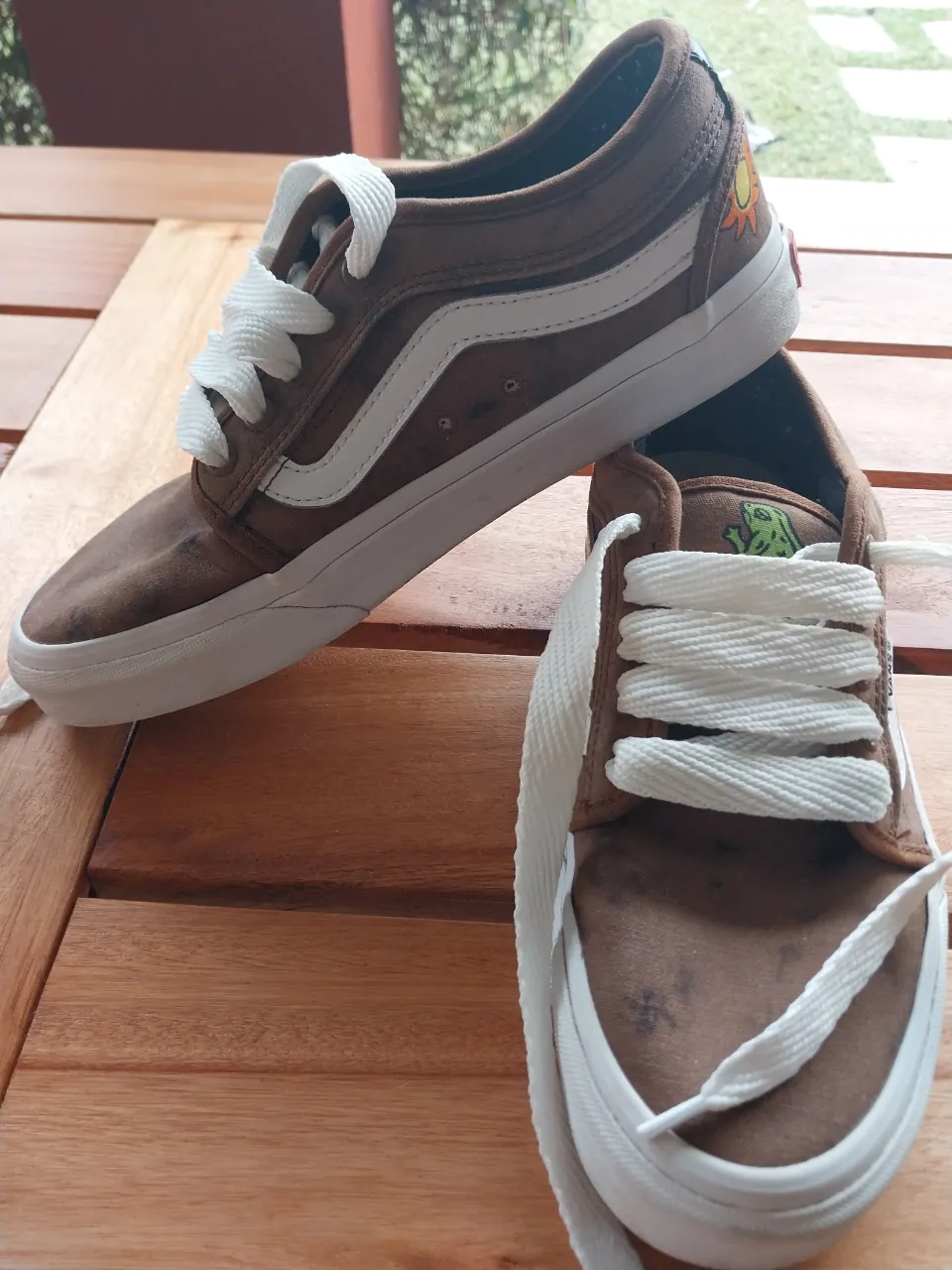 Zapatillas Vans marrones con detalles de dibujos y cordones blancos. Ideales para un look skater y casual.