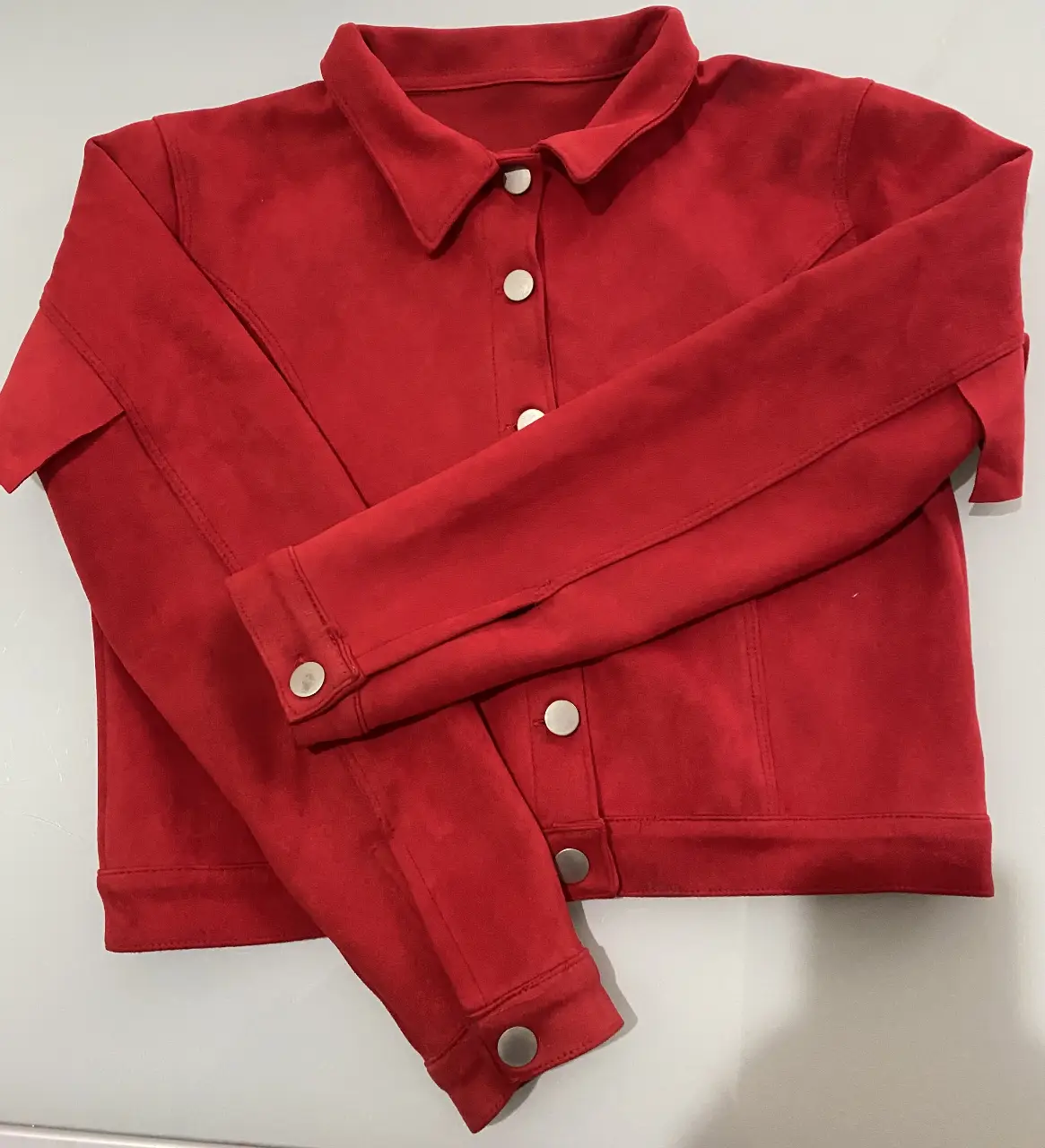Campera roja de gamuza con botones y detalle de volados en la espalda. Ideal para un look moderno y canchero.