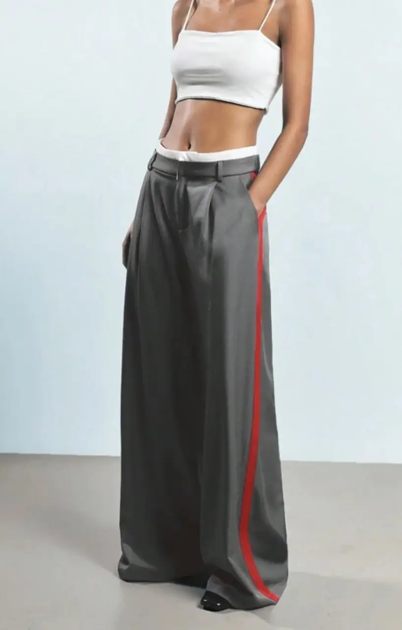 Pantalón sastrero gris con detalle de cinta roja lateral. Corte amplio y elegante, ideal para un look sofisticado.