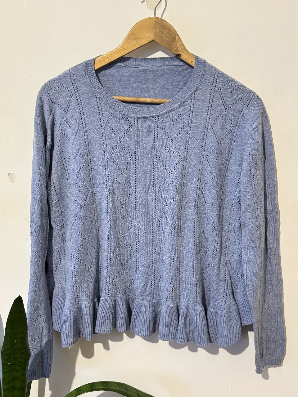 Sweater de punto azul claro con detalle de corazones calados y volados en el bajo. Cuello redondo y mangas largas. Ideal para un look casual y femenino.