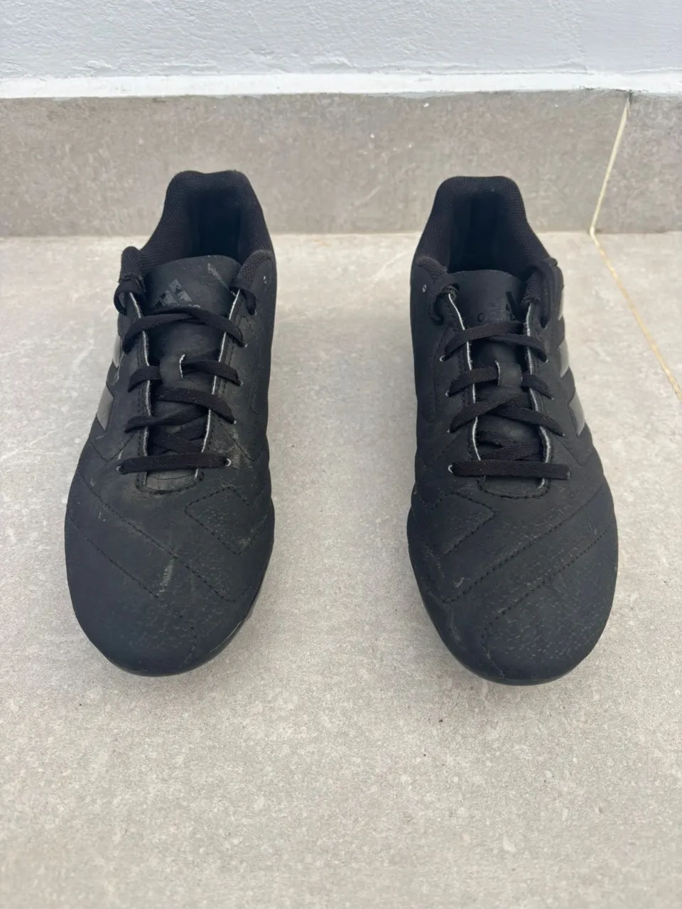 Botines de fútbol negros con cordones y suela con tapones. 