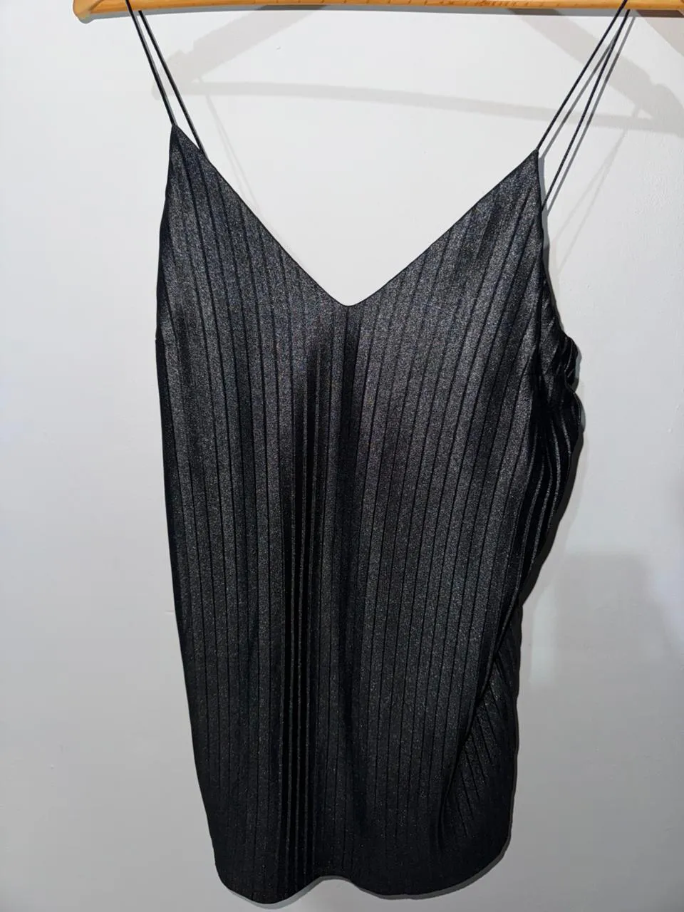 Top negro con tiras finas y escote en V. Posee un diseño de pliegues verticales en toda la prenda.