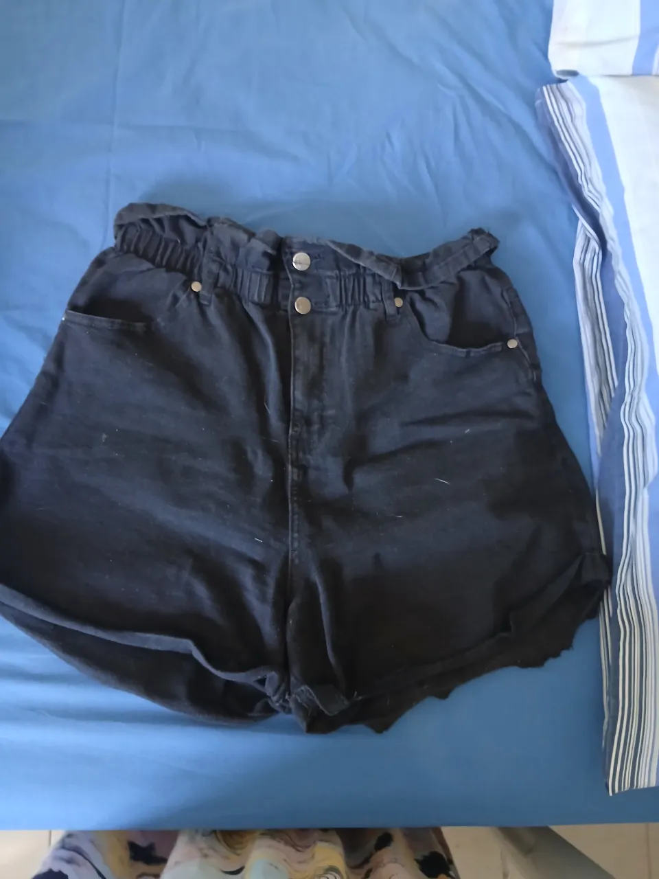 Shorts de jean negros con cintura elastizada y detalle de botones en la parte delantera.