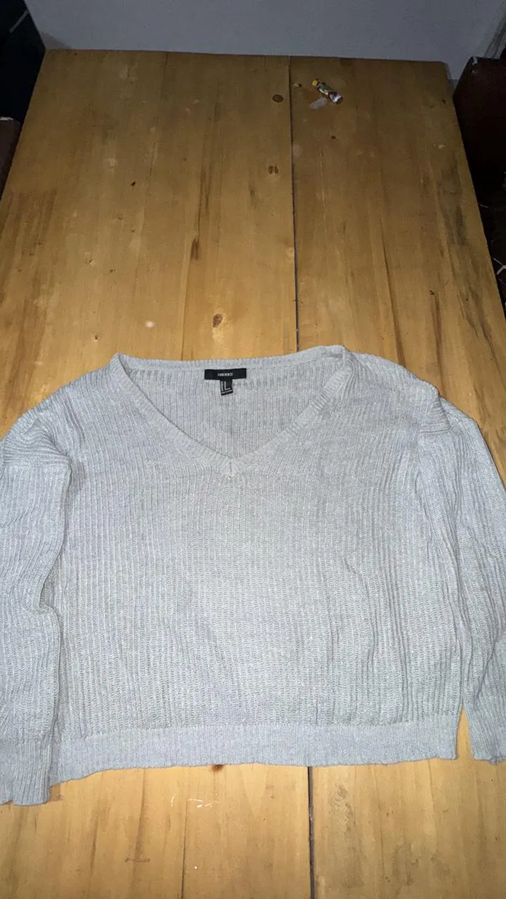 Sweater gris de tejido de punto con cuello en V y mangas largas.