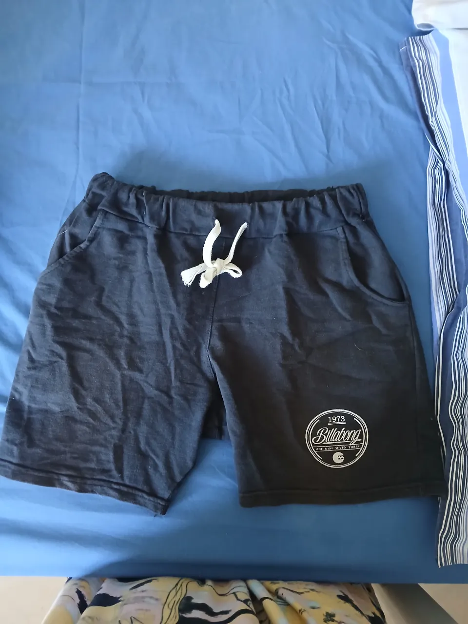 Shorts de algodón negro con cordón blanco para ajustar la cintura. Posee bolsillos laterales y un logo circular estampado en la pierna derecha.