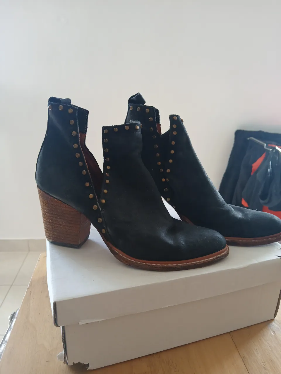 Botas negras de cuero con tachas doradas y taco de madera.