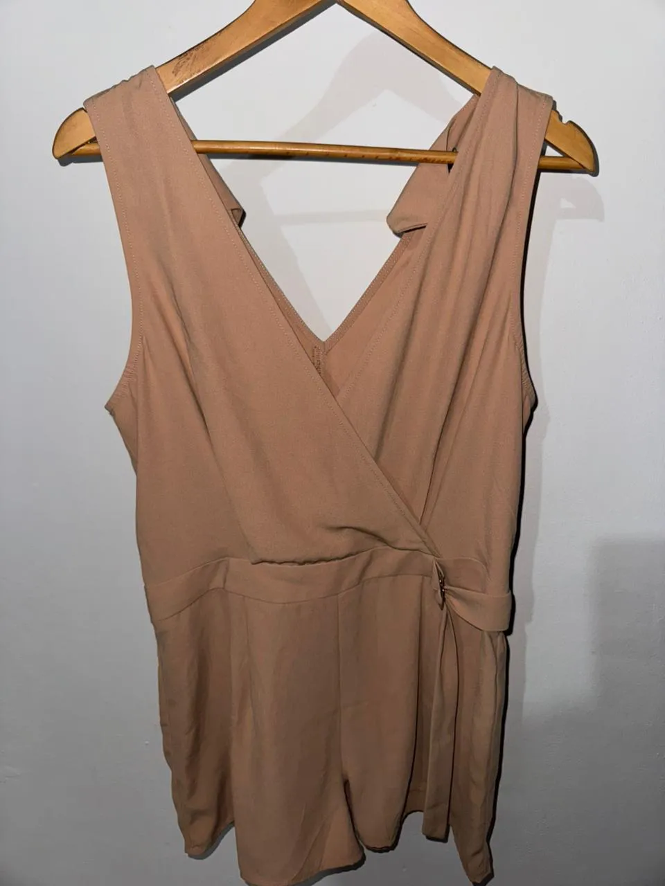 Mono color tiza, sin mangas, con escote en V cruzado y detalle de lazo en la cintura.