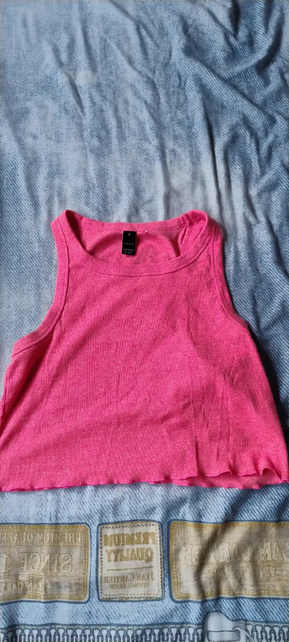 Musculosa de color rosa vibrante, con cuello redondo y terminación desflecada en la parte inferior.