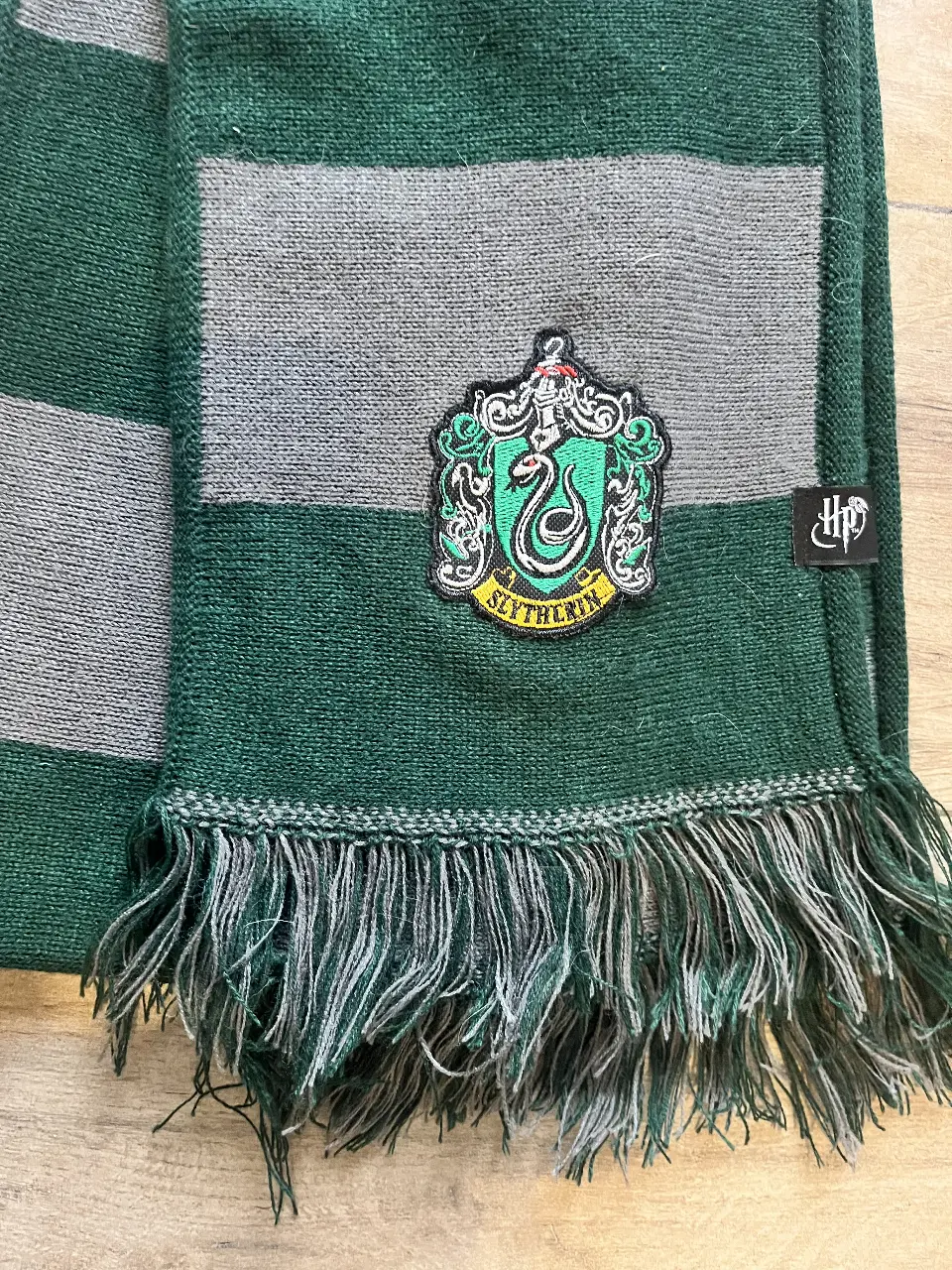 Bufanda de Slytherin, ideal para fanáticos de Harry Potter. Con los colores de la casa y el escudo bordado.