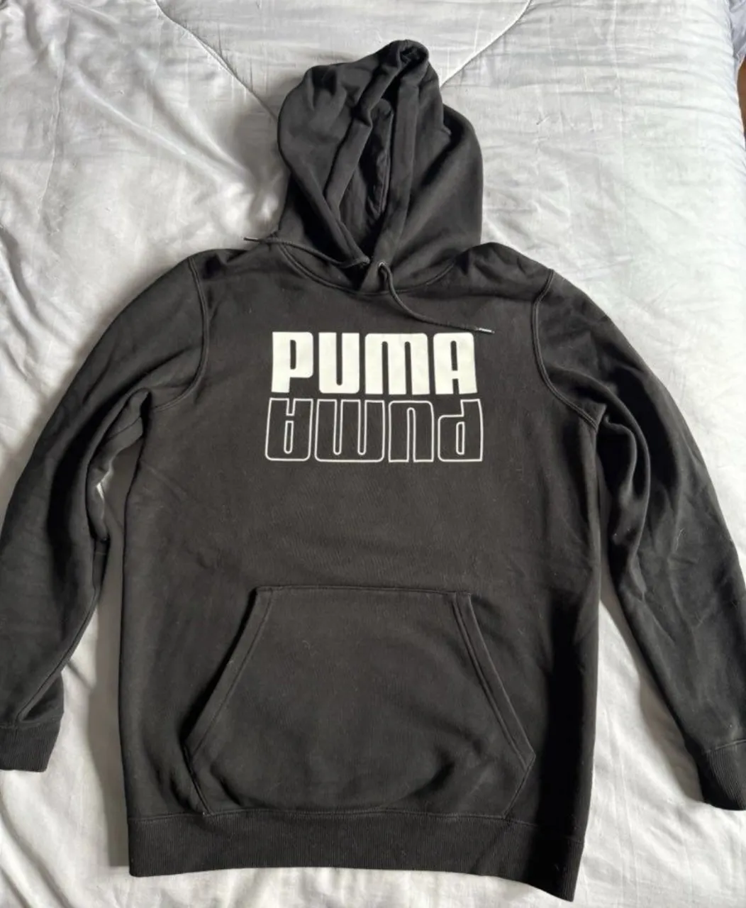 Buzo negro con capucha y cordones. Estampa blanca con el logo de la marca en el frente. Bolsillo tipo canguro.