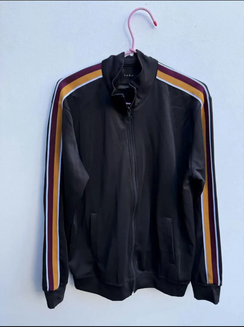 Buzo deportivo con cierre de la marca Zara, color negro con detalles en amarillo y bordó en las mangas. Ideal para un look casual y cómodo.